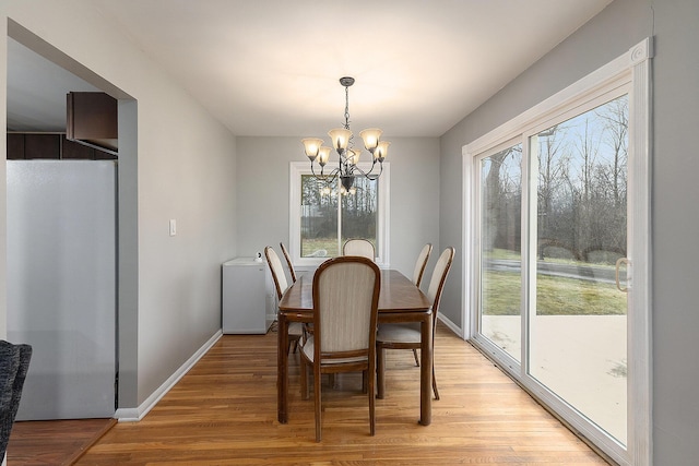 dining space with light hardwood / wood-style flooring and a notable chandelier