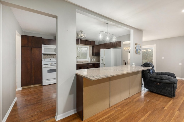 kitchen featuring white appliances, sink, hardwood / wood-style flooring, tasteful backsplash, and dark brown cabinets