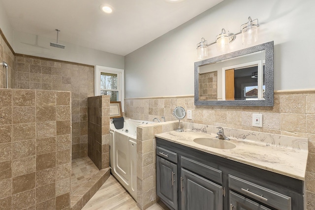 bathroom with hardwood / wood-style floors, vanity, tile walls, and shower with separate bathtub