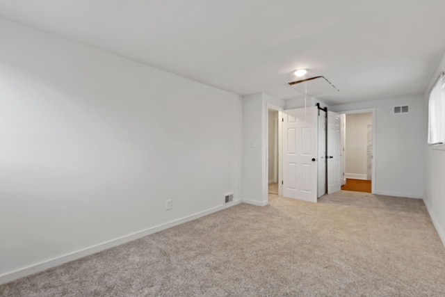 spare room featuring carpet floors, visible vents, and baseboards