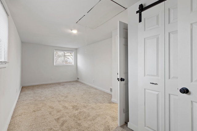 empty room with a barn door and light colored carpet