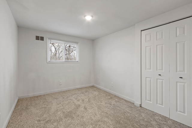 unfurnished bedroom with carpet floors, a closet, visible vents, and baseboards