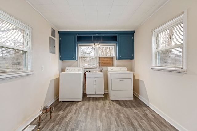 laundry room featuring cabinet space, electric panel, washing machine and clothes dryer, light wood-style floors, and a sink