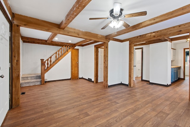 unfurnished living room featuring hardwood / wood-style flooring, ceiling fan, and beam ceiling