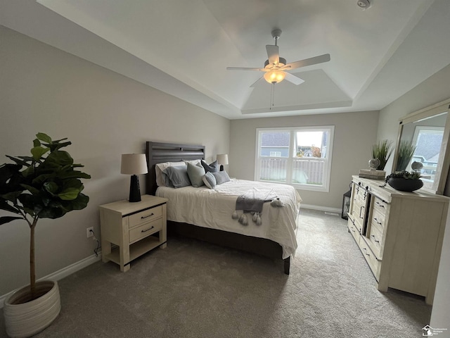 carpeted bedroom featuring ceiling fan and a raised ceiling