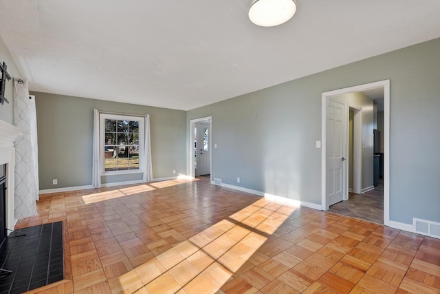 unfurnished living room featuring light parquet flooring and a brick fireplace