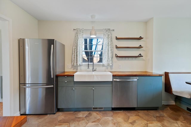 kitchen featuring wood counters, sink, gray cabinets, decorative light fixtures, and stainless steel appliances