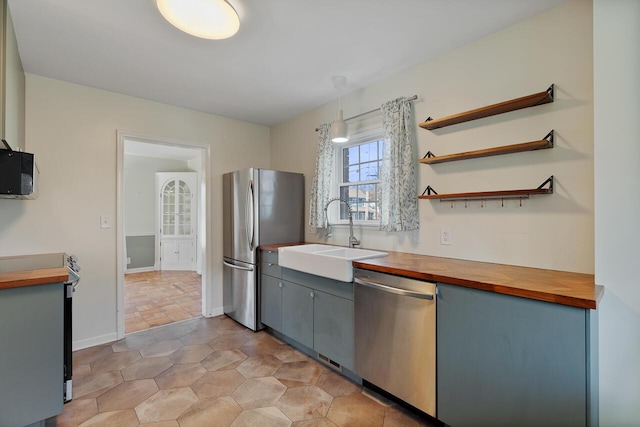 kitchen with wooden counters, decorative light fixtures, stainless steel appliances, and sink