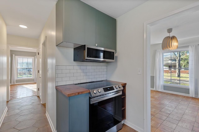 kitchen featuring wooden counters, appliances with stainless steel finishes, backsplash, and a wealth of natural light