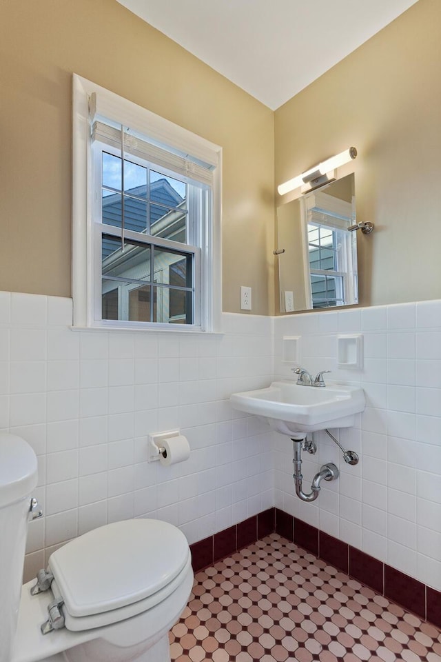 bathroom featuring sink, plenty of natural light, tile walls, and toilet