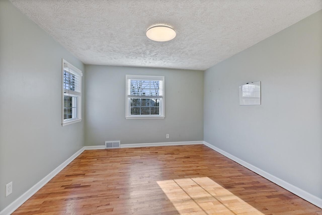 empty room with light hardwood / wood-style floors and a textured ceiling