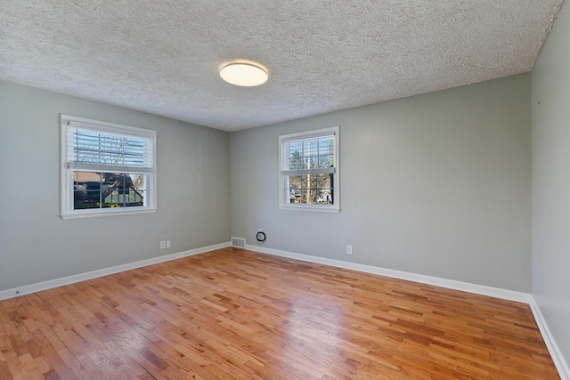 empty room featuring a textured ceiling and light hardwood / wood-style floors