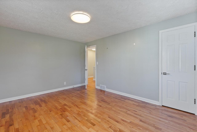 unfurnished room featuring a textured ceiling and light hardwood / wood-style flooring