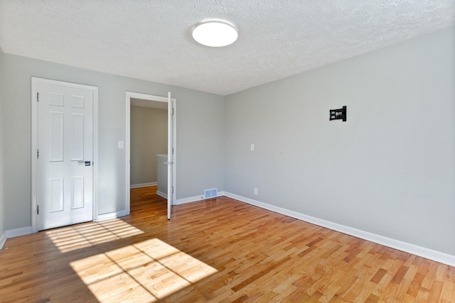 unfurnished room with hardwood / wood-style floors and a textured ceiling