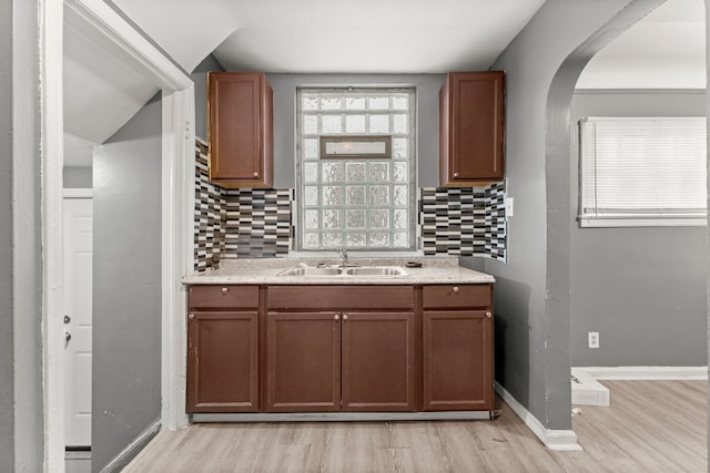 kitchen featuring decorative backsplash, sink, and light wood-type flooring