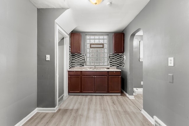 kitchen with decorative backsplash, light wood-type flooring, and sink