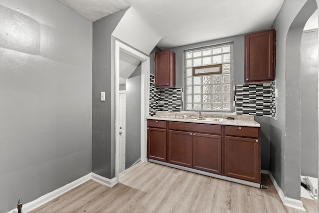 kitchen with sink, light wood-type flooring, and backsplash