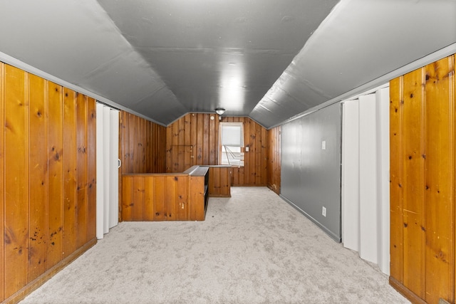 bonus room with wood walls, light carpet, and vaulted ceiling