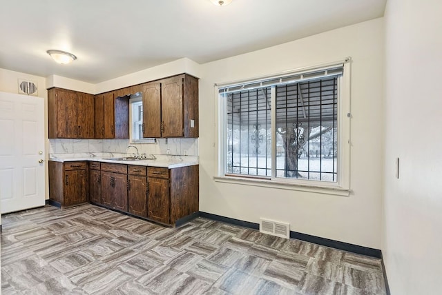 kitchen featuring decorative backsplash, dark brown cabinets, and sink