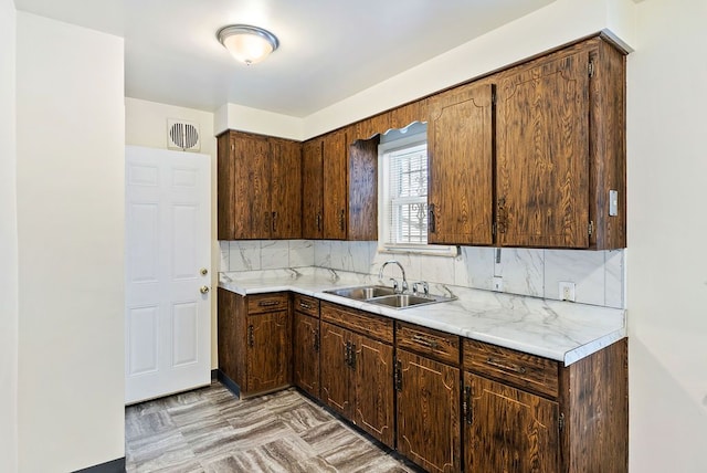 kitchen with dark brown cabinets, decorative backsplash, and sink