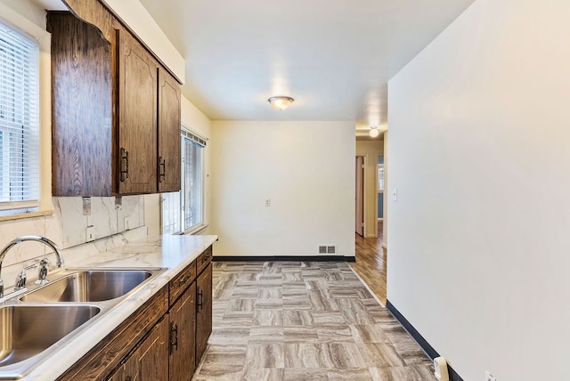 kitchen with plenty of natural light, dark brown cabinets, and sink