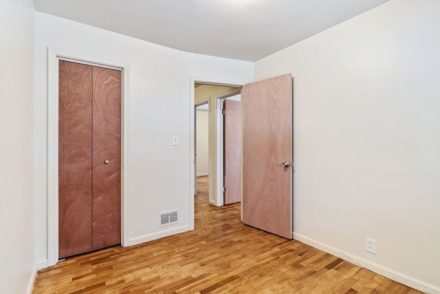 unfurnished bedroom with a closet and light wood-type flooring