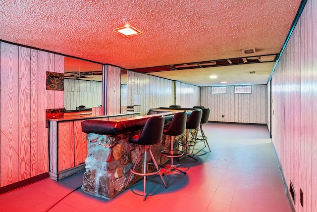 bar featuring wood walls and a textured ceiling