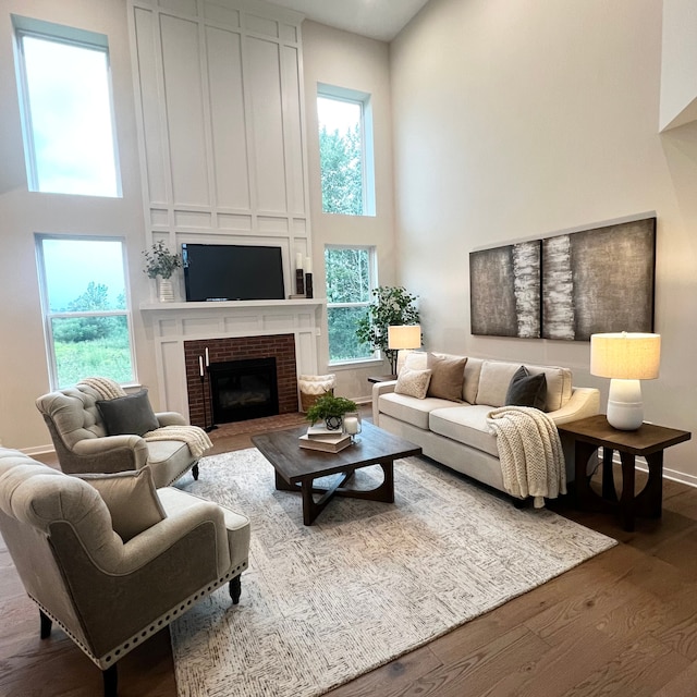 living room featuring a high ceiling, hardwood / wood-style flooring, and a brick fireplace