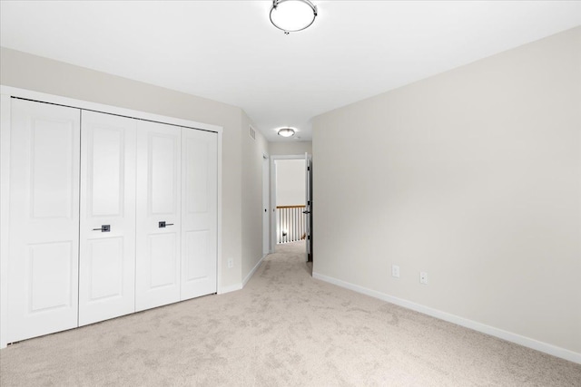 unfurnished bedroom featuring light colored carpet and a closet