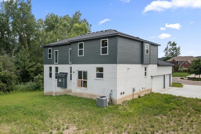 back of property with a lawn, cooling unit, and a garage