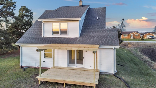 back house at dusk with a wooden deck and a yard