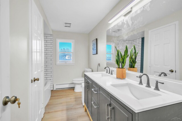 full bathroom with vanity, baseboard heating, shower / bathing tub combination, hardwood / wood-style flooring, and toilet