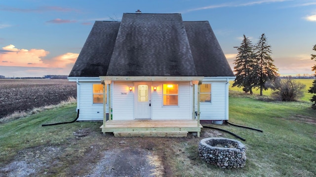 exterior space with a porch, a yard, and a fire pit