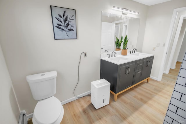 bathroom with hardwood / wood-style flooring, vanity, toilet, and a baseboard heating unit