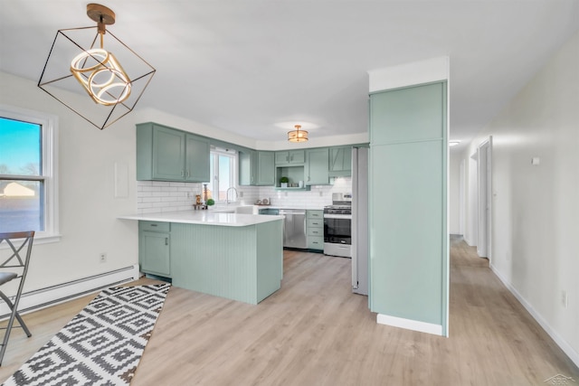 kitchen featuring backsplash, green cabinetry, decorative light fixtures, kitchen peninsula, and stainless steel appliances