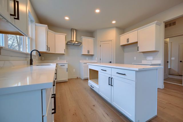 kitchen featuring sink, white cabinets, wall chimney range hood, and a kitchen island