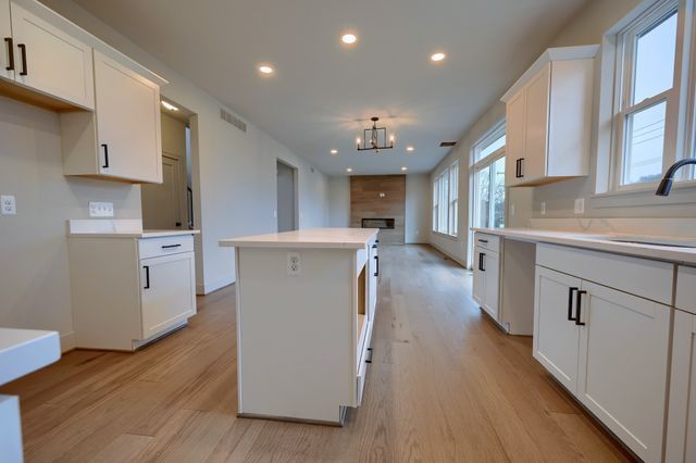 kitchen featuring a fireplace, white cabinetry, a kitchen island, and sink