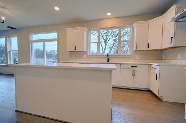 kitchen with a kitchen island, light hardwood / wood-style flooring, white cabinetry, and wall chimney exhaust hood