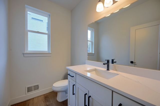 bathroom featuring hardwood / wood-style floors, vanity, a healthy amount of sunlight, and toilet