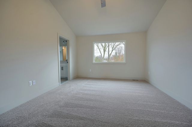 carpeted spare room featuring high vaulted ceiling