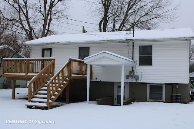 snow covered back of property featuring central AC unit and a deck