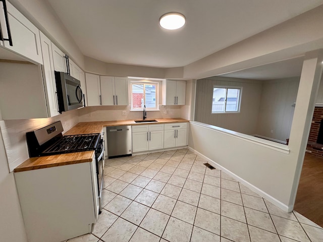 kitchen with gas range, dishwasher, sink, butcher block countertops, and white cabinets