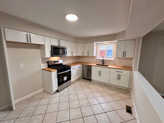 kitchen with white cabinets, butcher block countertops, sink, and appliances with stainless steel finishes