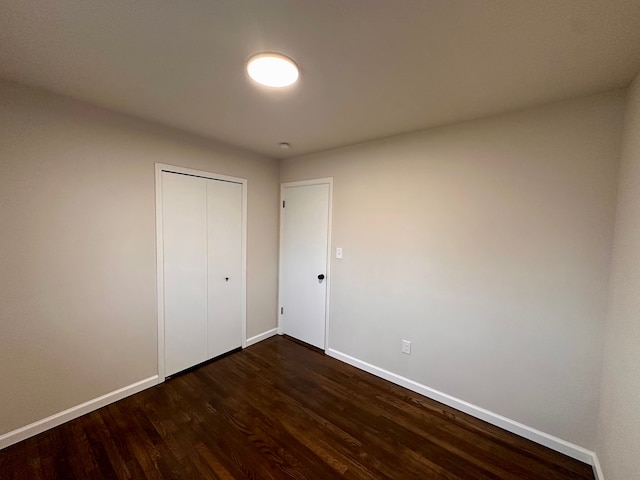 unfurnished bedroom featuring dark hardwood / wood-style flooring and a closet