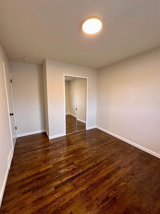 unfurnished bedroom with dark hardwood / wood-style flooring and a closet