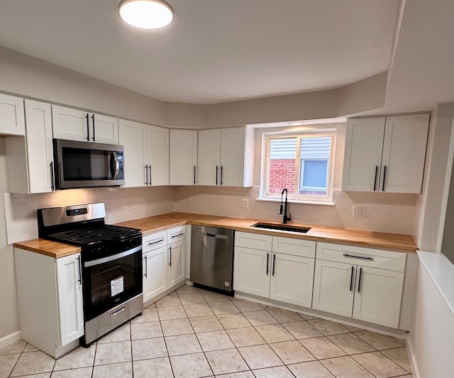 kitchen with white cabinets, wood counters, sink, and appliances with stainless steel finishes