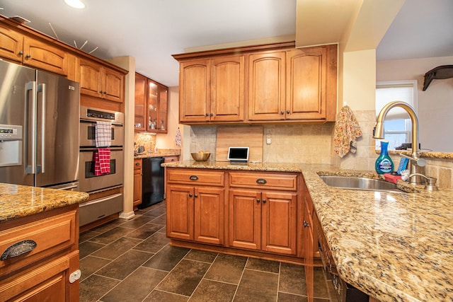 kitchen with decorative backsplash, light stone countertops, sink, and appliances with stainless steel finishes