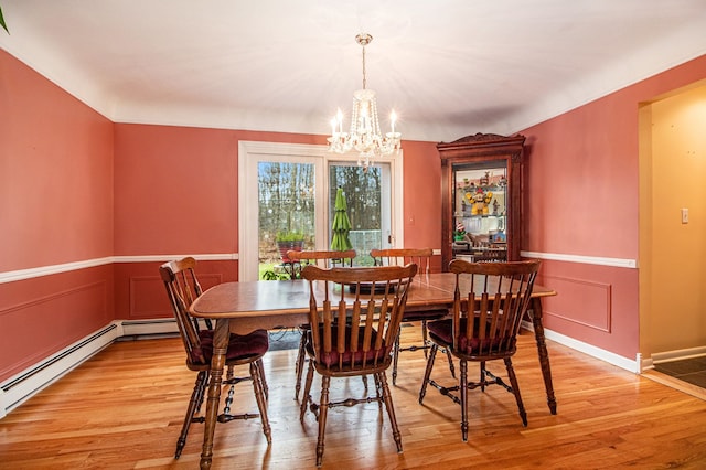 dining area featuring an inviting chandelier, a baseboard radiator, and light wood-type flooring