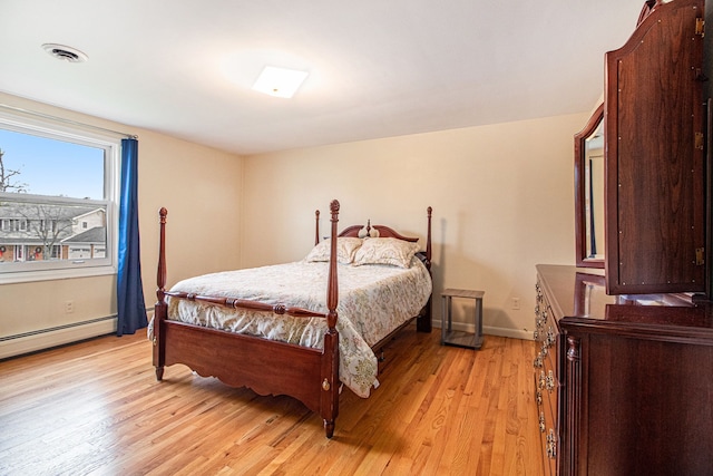 bedroom with light hardwood / wood-style flooring and a baseboard heating unit