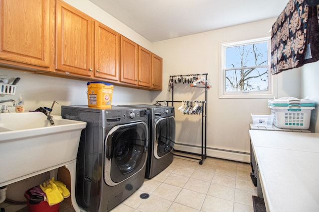 laundry room featuring cabinets, baseboard heating, sink, light tile patterned floors, and washing machine and dryer